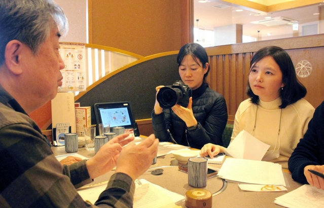 明石歩道橋事故の遺族、白井義道さん（左端）を取材する韓国の週刊誌「時事ＩＮ」の全慧願記者（右）ら＝１月３日、明石市樽屋町