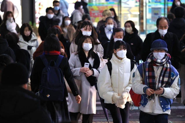 マフラーやダウンジャケットなど厚着で街を歩く人ら＝２３日午後、神戸市中央区三宮町１