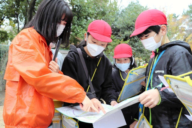 フィールドワークで児童に寄り添う神戸学院大の学生（左）ら＝神戸市灘区