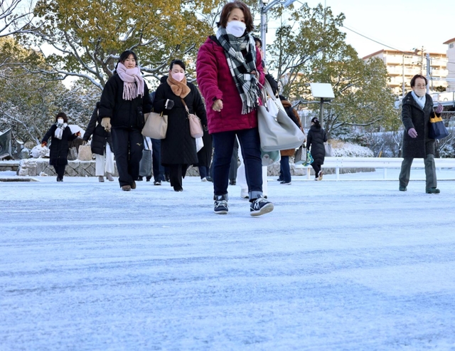 真っ白になった横断歩道を慎重に歩く人たち＝２５日午前８時２２分、神戸市須磨区中落合２