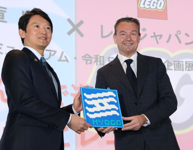 レゴブロックで作られた兵庫県旗を手に、企画展について発表する斎藤元彦知事（左）とマイケル・エベスン代表取締役＝神戸市兵庫区中之島２