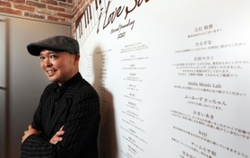 クラウドファンディングで寄せられた応援のメッセージに支えられたという片山行茂代表。ライブハウス「ソープ・オペラ・クラシックス梅田」の入り口に大きく掲示している＝大阪市北区西天満４