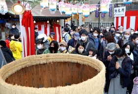 酒樽にさい銭を投げ入れ、手を合わせる参拝客ら＝９日、神戸市兵庫区西柳原町、蛭子神社（撮影・長嶺麻子）