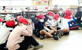 神戸市内の小学校で行われた避難訓練。余震も想定し、子どもたちは頭を手で押さえた＝２０２２年１１月（撮影・中西幸大）