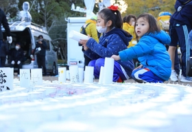 紙灯籠の準備を手伝う子どもたち＝１６日午後、神戸市中央区加納町６、東遊園地