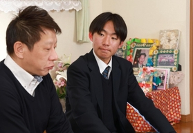 阪神・淡路大震災で亡くなった伯父・崔秀光さんの遺影を背に、父の秀英さん（左）の経験を継承していこうと決意する崔雄貴さん＝神戸市須磨区千歳町１