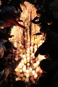 紙灯籠に火をともすボランティアら＝１６日午後、神戸市中央区加納町６、東遊園地