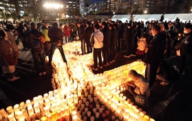 紙灯籠に灯をともし、黙とうする市民ら＝１６日午後５時４６分、神戸市中央区加納町６、東遊園地