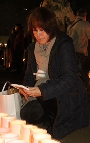 母の正子さんの遺影と目を合わせる佐藤悦子さん＝１７日午前６時１７分、神戸市中央区、東遊園地
