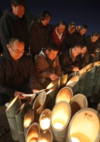 竹灯籠を前に祈りをささげる宮城県名取市の被災者ら＝１７日午前、神戸市中央区加納町６