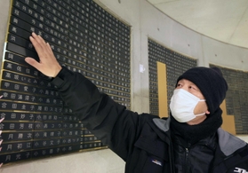 母と妹の名前が刻まれた銘板に触れる山田克敏さん＝１７日午前５時５８分、神戸市中央区加納町６、東遊園地