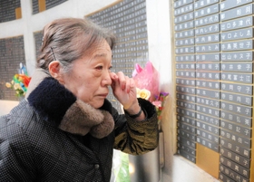 母の名を見て涙ぐむ出口恵美子さん＝１７日午前９時３４分、神戸市中央区加納町６、東遊園地