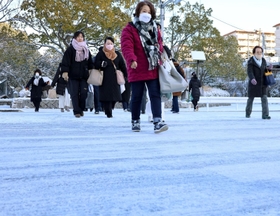真っ白になった横断歩道を慎重に歩く人たち＝２５日午前８時２２分、神戸市須磨区中落合２