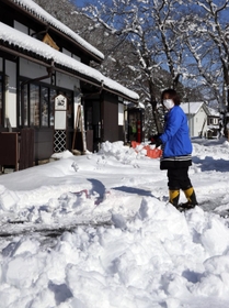 ＪＲ竹田駅前で雪かきをする女性。１月の観測史上最低となる冷え込みを記録した＝２６日午前、朝来市和田山町竹田