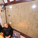アクリル板で覆った壁を見上げる木下大輔さん（左）と一夫さん。震災の傷もサインも、はっきりと確認できる＝神戸市須磨区大田町２