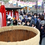 酒樽にさい銭を投げ入れ、手を合わせる参拝客ら＝９日、神戸市兵庫区西柳原町、蛭子神社（撮影・長嶺麻子）