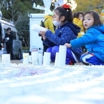 紙灯籠の準備を手伝う子どもたち＝１６日午後、神戸市中央区加納町６、東遊園地