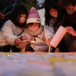 紙灯籠に火をともす子どもら＝１６日午後、神戸市中央区加納町６、東遊園地