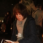 母の正子さんの遺影と目を合わせる佐藤悦子さん＝１７日午前６時１７分、神戸市中央区、東遊園地