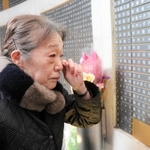 母の名を見て涙ぐむ出口恵美子さん＝１７日午前９時３４分、神戸市中央区加納町６、東遊園地