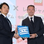レゴブロックで作られた兵庫県旗を手に、企画展について発表する斎藤元彦知事（左）とマイケル・エベスン代表取締役＝神戸市兵庫区中之島２