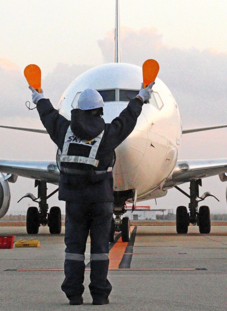 パドルを持って機体に停止位置を知らせるマーシャラー＝神戸市中央区、神戸空港