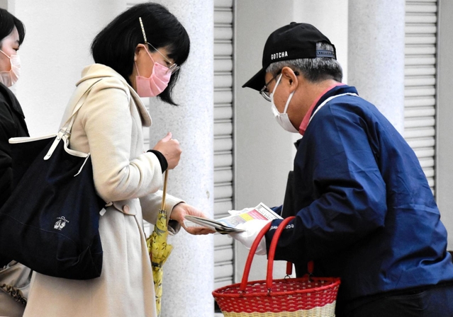 事件解決への情報提供を求め、通行人らにビラを配る寺田和子さんの夫（右）＝１９日午前、神戸市須磨区横尾１