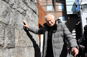 神戸ジューコムの石垣に触れ、目を閉じて思い出を振り返るマルセル・ウェイランドさん＝中央区山本通１