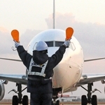 パドルを持って機体に停止位置を知らせるマーシャラー＝神戸市中央区、神戸空港