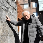 神戸ジューコムの石垣に触れ、目を閉じて思い出を振り返るマルセル・ウェイランドさん＝中央区山本通１