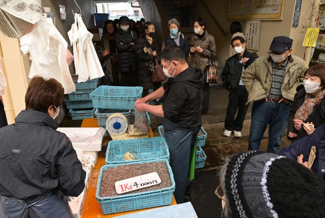 漁の解禁初日、新鮮なイカナゴのシンコ（稚魚）を求めて大勢の人が並んだ＝４日午前、神戸市兵庫区東山町、東山商店街
