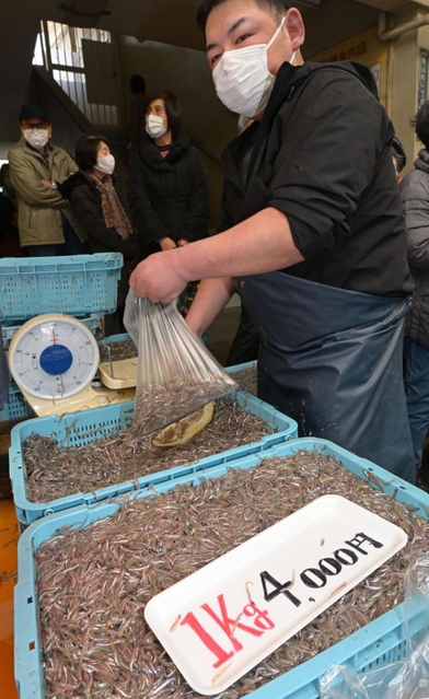 客の注文を受けてイカナゴのシンコ（稚魚）を袋に入れる鮮魚店員＝４日午前、神戸市兵庫区東山町、東山商店街
