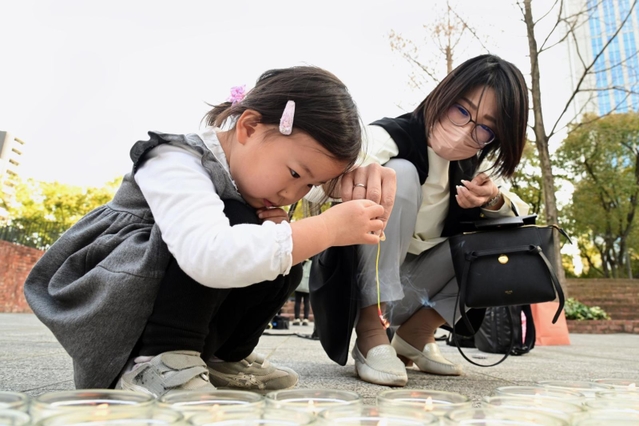 キャンドルの火で線香花火をつけて、東日本大震災の被災地に思いをはせる参加者＝１１日午後、神戸市中央区加納町６、東遊園地