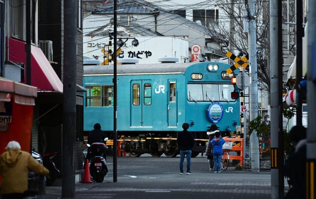 ＪＲ和田岬駅に到着する１０３系。商店街のすぐそばを通るその姿を住民らがカメラに収めていた＝神戸市兵庫区小松通２