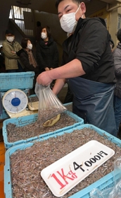 客の注文を受けてイカナゴのシンコ（稚魚）を袋に入れる鮮魚店員＝４日午前、神戸市兵庫区東山町、東山商店街