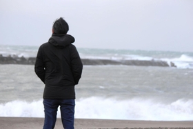 荒れる日本海を見つめる男性