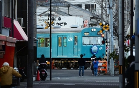 ＪＲ和田岬駅に到着する１０３系。商店街のすぐそばを通るその姿を住民らがカメラに収めていた＝神戸市兵庫区小松通２