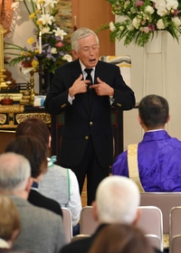 手話と身ぶりで神戸空襲の悲惨さを伝える山村賢二さん＝２０１８年３月１７日、神戸市兵庫区今出在家町４、薬仙寺