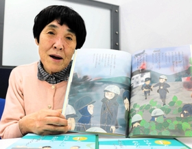 絵本「手をはなしたらあかん」を紹介する小城智子さん。「山村さんが直接伝えられる子どもの数は限られているけれど、絵本が伝えてくれる」＝神戸新聞社