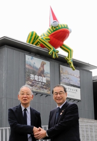 ３代目の「美かえる」を背景に握手する蓑豊・兵庫県立美術館長（左）と家次恒・シスメックス会長兼社長＝神戸市中央区脇浜海岸通１