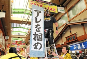 阪神タイガースの優勝を祈って、マジック「１４３」を取り付けた、尼崎中央３丁目商店街の名誉応援団長プロレスラー空牙（くうが）さん＝２９日午前、尼崎市神田中通３