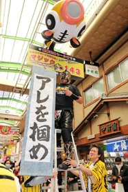 阪神タイガースの優勝を祈って、マジック「１４３」を取り付けた、尼崎中央３丁目商店街の名誉応援団長プロレスラー空牙（くうが）さん＝２９日午前、尼崎市神田中通３