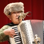 友好の願いを込めてロシア製のミンク帽をかぶり、シベリア抑留体験を弾き語る田中唯介さん＝兵庫県播磨町中央公民館
