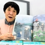 絵本「手をはなしたらあかん」を紹介する小城智子さん。「山村さんが直接伝えられる子どもの数は限られているけれど、絵本が伝えてくれる」＝神戸新聞社