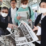 ＷＢＣで日本が優勝した号外を手にする人たち＝２２日午後、神戸市中央区、ＪＲ三ノ宮駅前（撮影・大森　武）