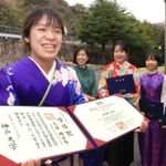 通称名が記載された学位記を手に、振り袖姿で同級生と門出を祝う久保明日香さん＝２４日午後、神戸市灘区、神戸大学（撮影・吉田敦史）