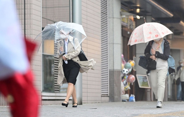 強風の中、傘を傾けながら歩く人ら＝７日午前、神戸市垂水区日向１（撮影・中西幸大）