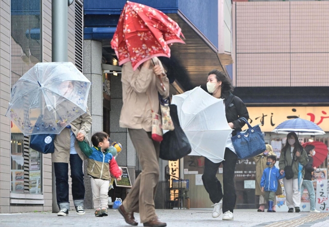 強風にあおられ、傘を傾けながら歩く人ら＝７日午前１０時５３分、神戸市垂水区日向１（撮影・中西幸大）
