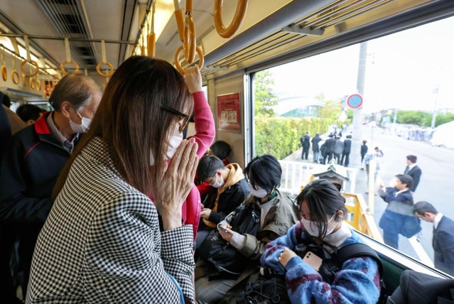 尼崎ＪＲ脱線事故から18年となり、現場を通過する電車内で手を合わせる女性＝25日午前９時16分、兵庫県尼崎市（代表撮影）