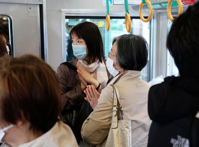 尼崎ＪＲ脱線事故から18年となり、現場近くを通過する電車内で手を合わせる乗客＝25日午前９時16分、兵庫県尼崎市（代表撮影）